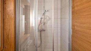 A glass-enclosed shower with a handheld showerhead and a wall-mounted faucet. - 2 bedroom amazing apartment in Liesing (Liesing)