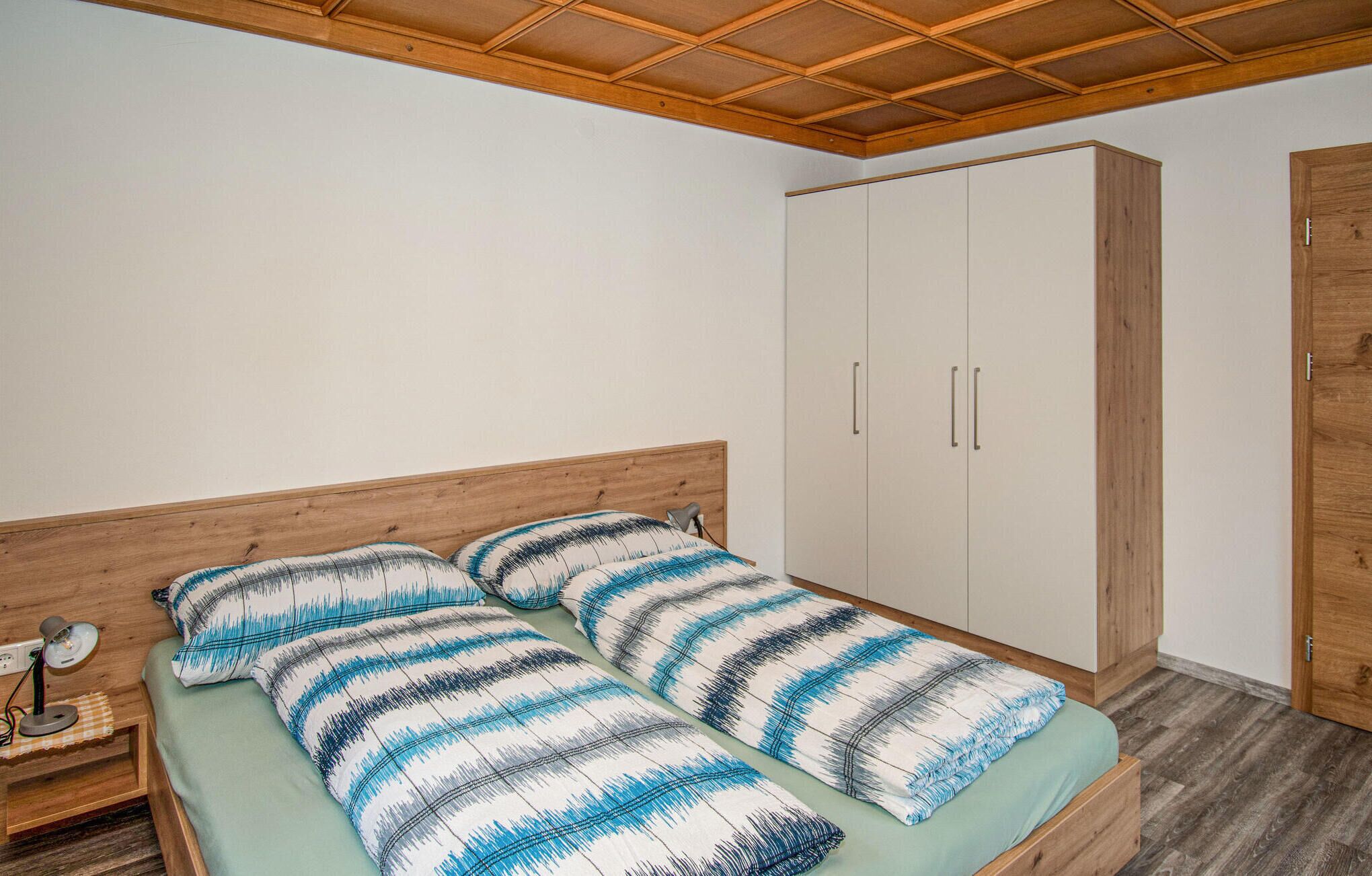 Een slaapkamer met een bed, nachtkastje, bureaulamp en een kledingkast.