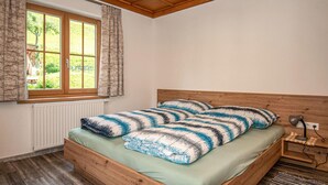 A bedroom with a wooden bed, a window with curtains, a radiator, and a bedside table with a lamp. - 2 bedroom amazing apartment in Liesing (Liesing)