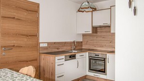 A compact kitchen with wooden cabinetry, a built-in oven, and a sink. - 2 bedroom amazing apartment in Liesing (Liesing)