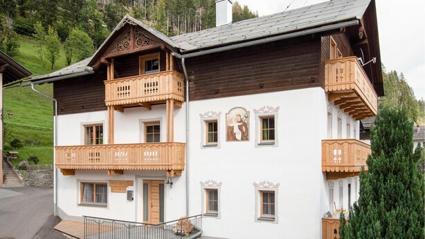 A traditional chalet with wooden balconies, a white facade, and a mountain backdrop. - 2 bedroom amazing apartment in Liesing (Liesing)