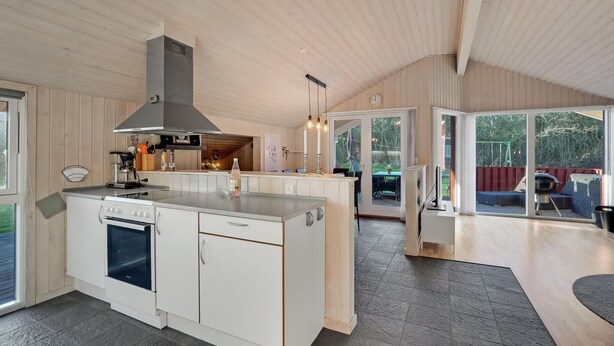 A modern kitchen with a central island, built-in oven, and a large window overlooking a deck. - Amazing home in Tarm with kitchen (Tarm)
