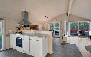 A modern kitchen with a central island, built-in oven, and a large window overlooking a deck. - Beautiful home in Tarm with sauna (Tarm)