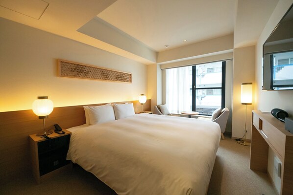 A hotel room with a large bed, bedside lamps, a desk, a chair, and a window with a view. - THE GENERAL KYOTO Bukkoji Shinmachi (Kyoto)
