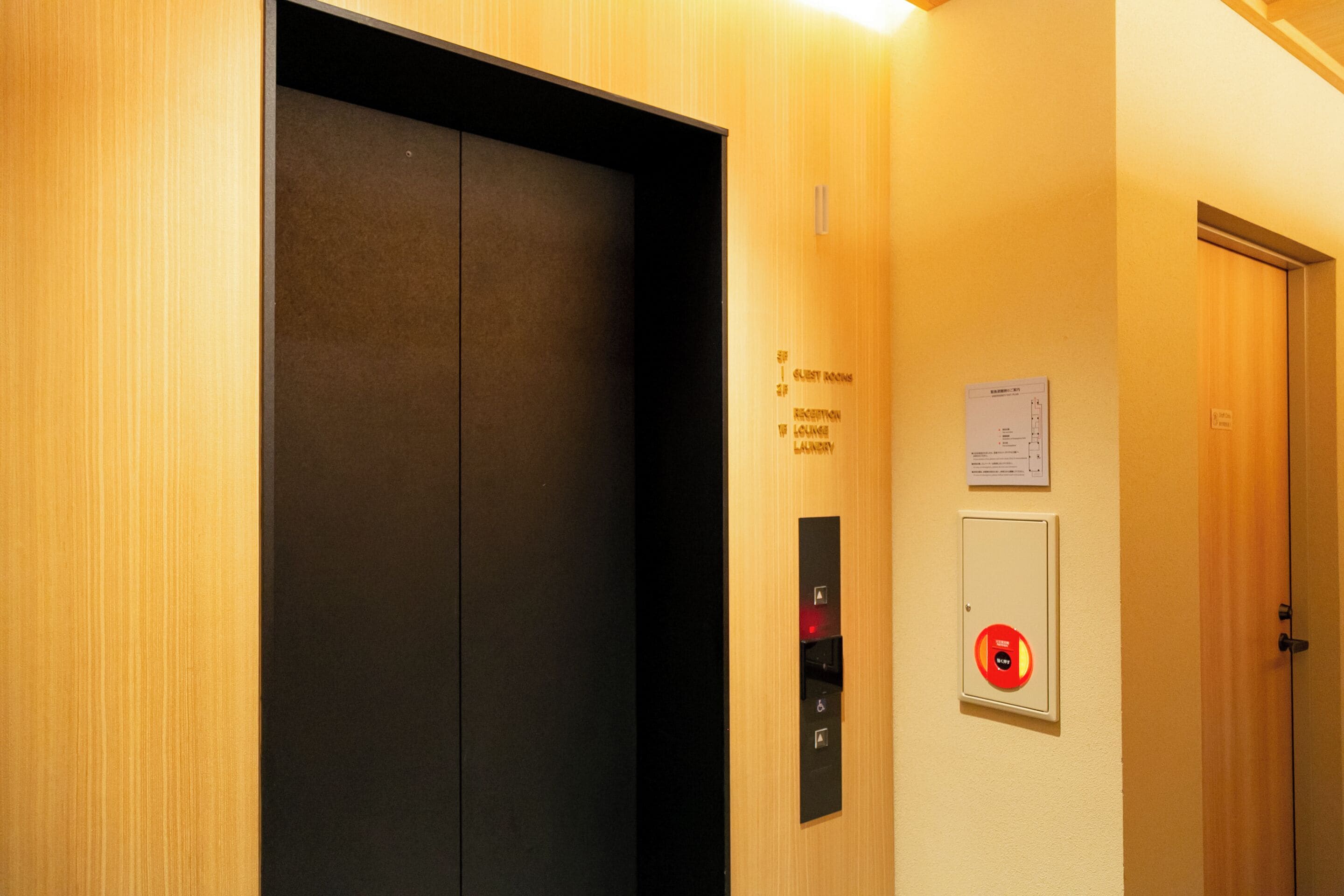 An elevator with a control panel and a sign indicating guest rooms.