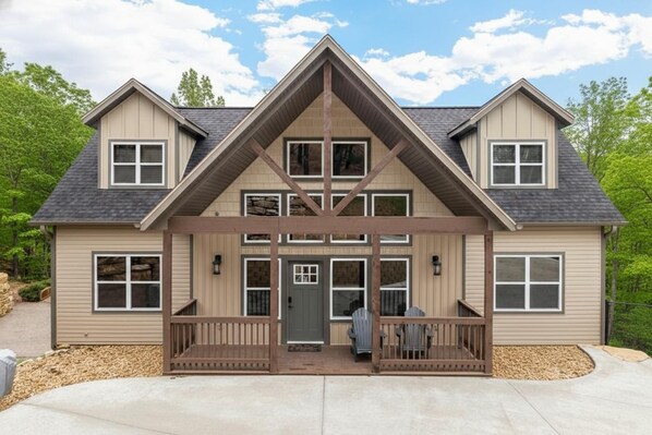 A two-story house with a symmetrical facade, a front porch with railings, and a small front yard.