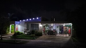 A modern building with a gated entrance, illuminated by overhead lights, and surrounded by greenery. - San Juan, Garden suite w/private POOL, outdoor kitchen/BBQ & peaceful (San Juan)