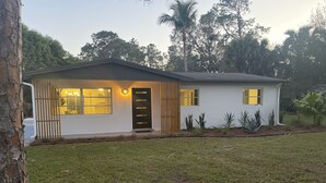 Een gelijkvloers huis met een veranda, een zichtbare garagepoort en een verzorgd gazon.