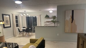 Een woonkamer met een bank, een eettafel met stoelen, een zwarte salontafel en een schilderij aan de muur.