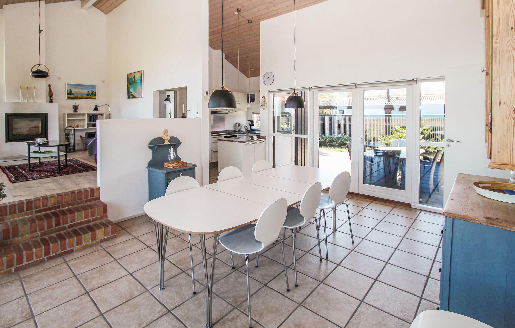Una cocina amplia con comedor, chimenea y vistas al exterior a través de puertas de vidrio.