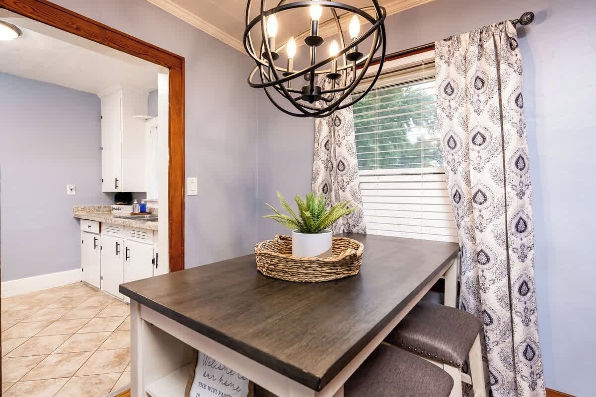 A kitchen with white cabinets, a dark wooden table, and a hanging light fixture.