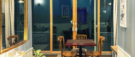 A dining area with a wooden table and chairs, a potted plant, and a mirror on the wall.