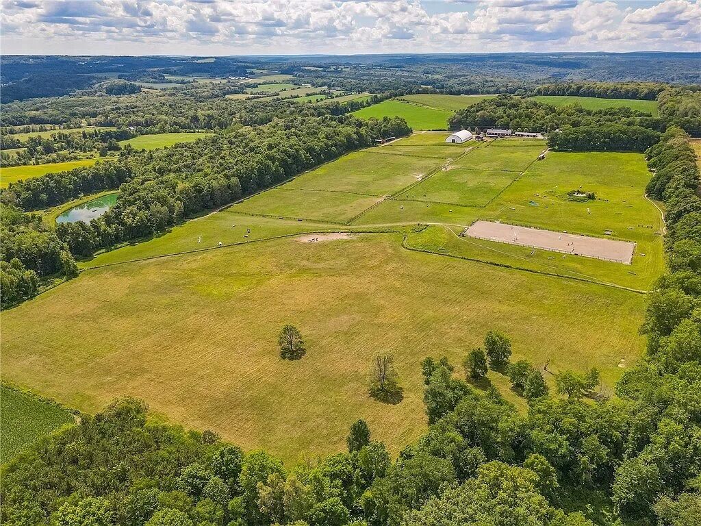 An aerial view of a large, open field with a few scattered trees and a small building.