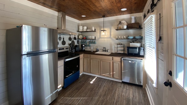 A modern kitchen with stainless steel appliances, wooden cabinets, and a farmhouse aesthetic.