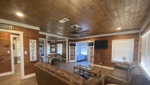 A spacious living room with a brown leather couch, a wooden coffee table, and a ceiling fan.