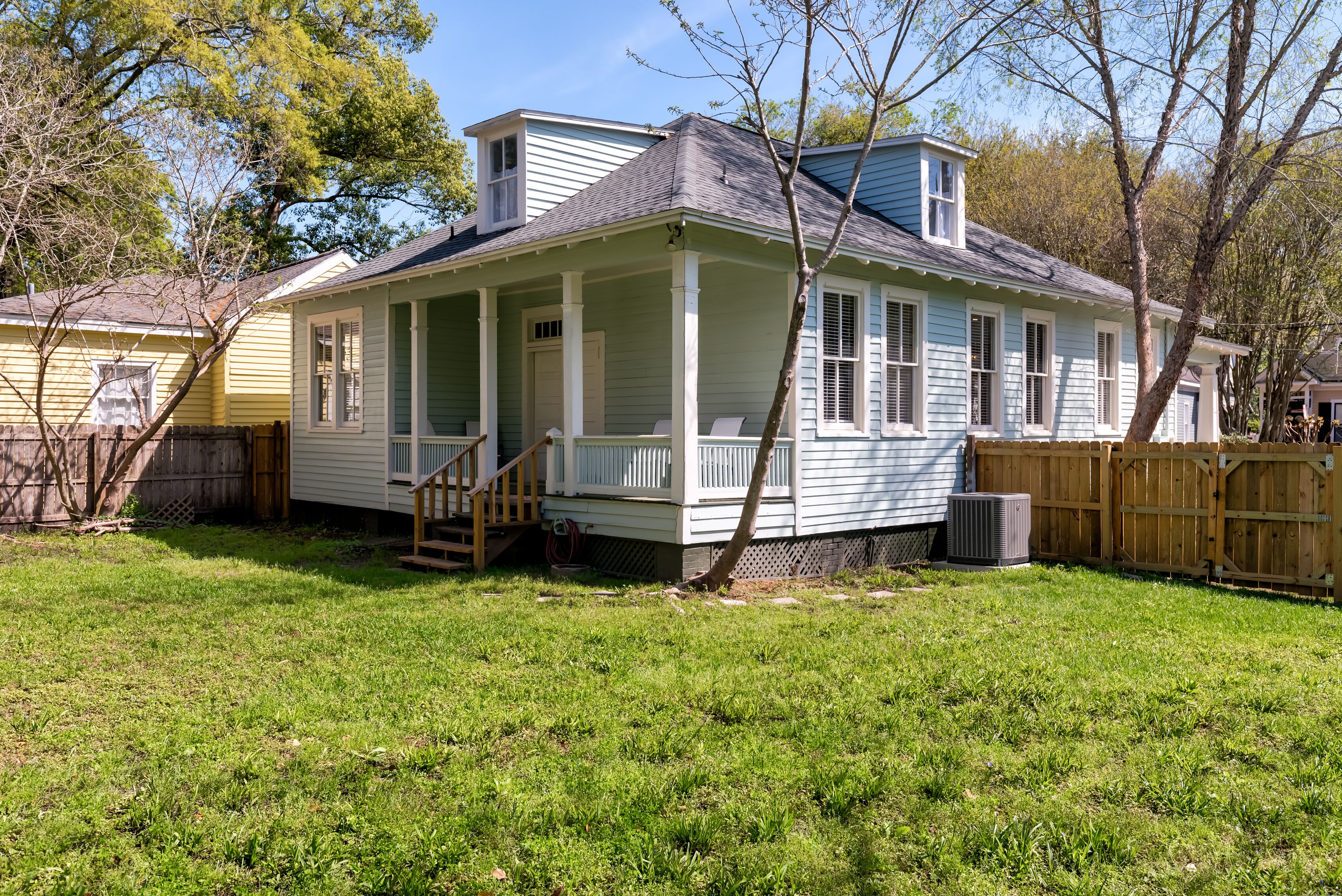 A two-story house with a porch, a small staircase, and a fenced yard.