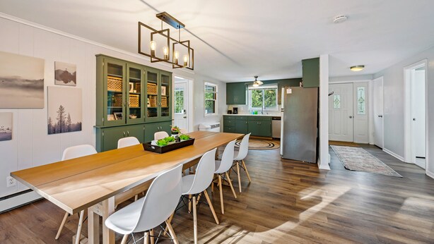A modern kitchen with a wooden table, white chairs, and green cabinets. - Cozy, Quiet and Peaceful Bailey's Harbor home: Close to Everything Door County! (Baileys Harbor)