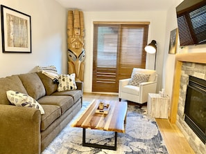 A living room with a sofa, armchair, coffee table, and fireplace.