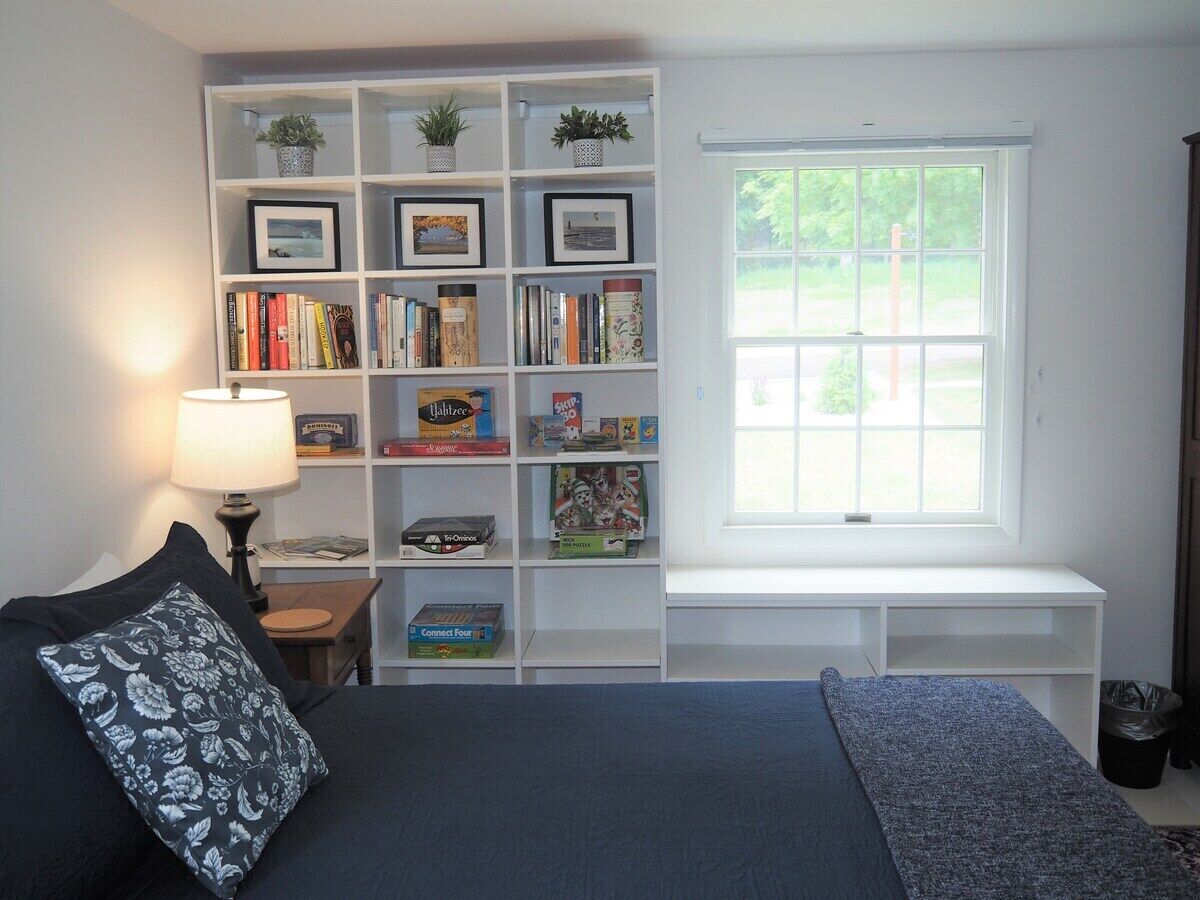 Une chambre à coucher avec un lit, une bibliothèque, un bureau et une fenêtre.