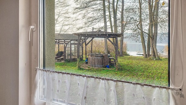 Une fenêtre donnant sur une structure en bois et un plan d’eau.