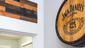 Een kamer met houten decoratie op de muur in de vorm van een vat, een ronde tafel met krukken, en een deur naar een andere kamer.
