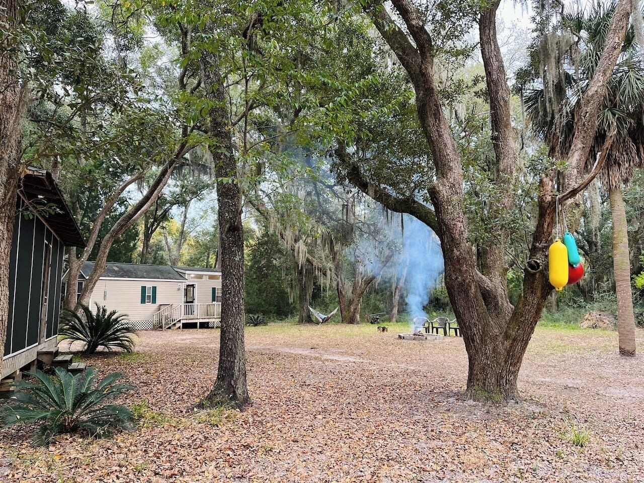 A cabin with a deck, surrounded by trees and a hammock.