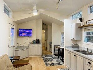 Enjoy a compact apartment with a modern kitchen, living area, and dining space, featuring an oven, microwave, and flat-screen TV.