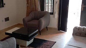 A living room with a sofa, a coffee table, and a rug. - Apartment Sleeps 4 with Balcony and Parking (Asaba)