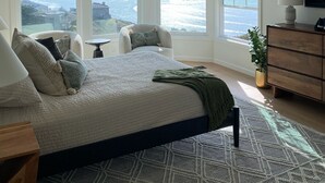 Ein Schlafzimmer mit einem großen Bett, einem Deckenventilator und Meerblick durch große Fenster.