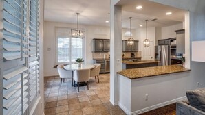 A modern kitchen with granite countertops, stainless steel appliances, and pendant lighting.