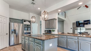 A modern kitchen with granite countertops, stainless steel appliances, and a central island.