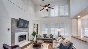 A spacious living room with a fireplace, modern furniture, and large windows.