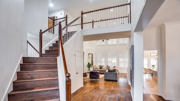A spacious living area with a wooden staircase, a sofa set, and a TV.