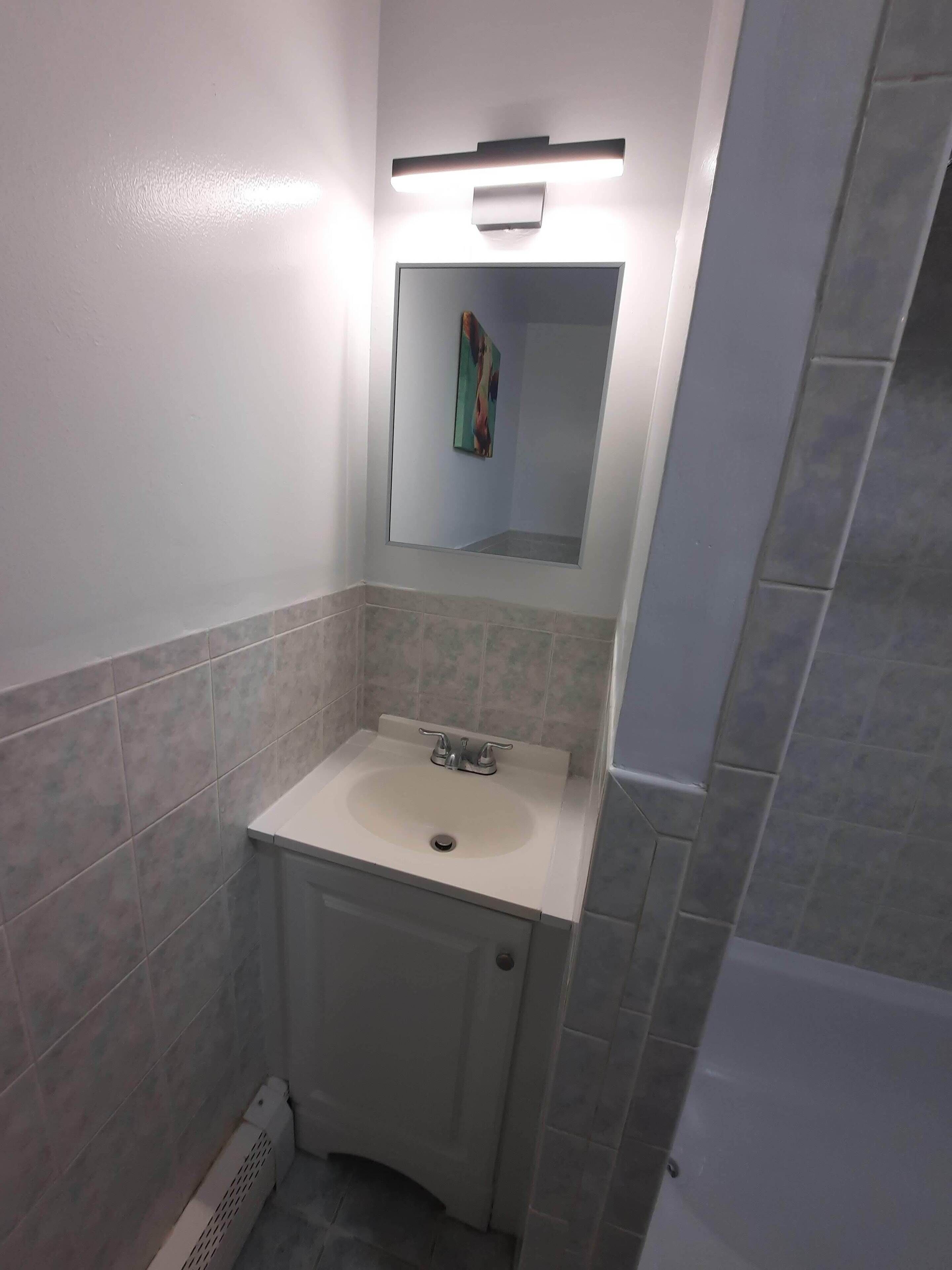 Un baño con lavamanos, espejo y lámpara.