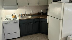 A kitchen with white cabinets, a stove, a sink, a microwave, and a refrigerator. - Two Bedroom Private Apt near NYC! (West New York)