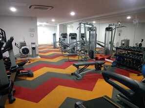 Ein Fitnessstudio mit verschiedenen Trainingsgeräten, einer Spiegelwand und einem chevron-gestreiften Teppich.