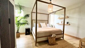 A four-poster bed with a woven basket and a hanging light fixture in a modern bedroom with wooden flooring and a large plant. - Aloha Moon - The Honeymoon Hideaway (Wailea)