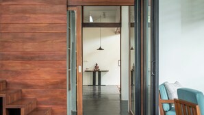 A modern interior with a wooden staircase, a dining area with a table and chairs, and a seating area with a blue chair. - 5BR Designer Eco-Villa, Private Pool (Krong Siem Reap)
