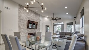 A modern living room with a glass dining table, grey sofas, and a stone accent wall. - Walking distance to Scottsdale sports complex, Barrett Jackson, and Phoenix Open (Scottsdale)