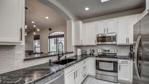A modern kitchen with white cabinetry, stainless steel appliances, and a black marble countertop. - Walking distance to Scottsdale sports complex, Barrett Jackson, and Phoenix Open (Scottsdale)