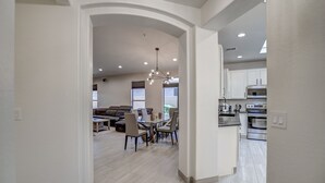 A modern kitchen with white cabinets and stainless steel appliances, a dining area with a glass table and chairs, and a living room with a sofa and coffee table. - Walking distance to Scottsdale sports complex, Barrett Jackson, and Phoenix Open (Scottsdale)