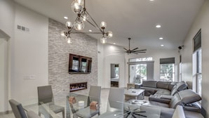 A modern living room with a glass dining table, leather sofa, fireplace, and a ceiling fan. - Walking distance to Scottsdale sports complex, Barrett Jackson, and Phoenix Open (Scottsdale)