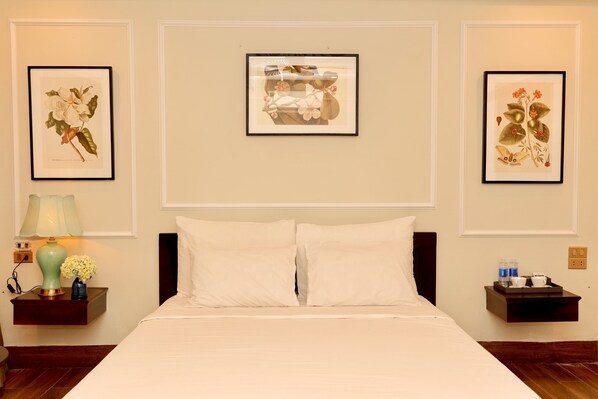 A neatly arranged hotel room with a large bed, two bedside tables, and framed botanical prints on the walls. - Lalita Tam Coc Resort & Spa  (Nam Hoa Lu)
