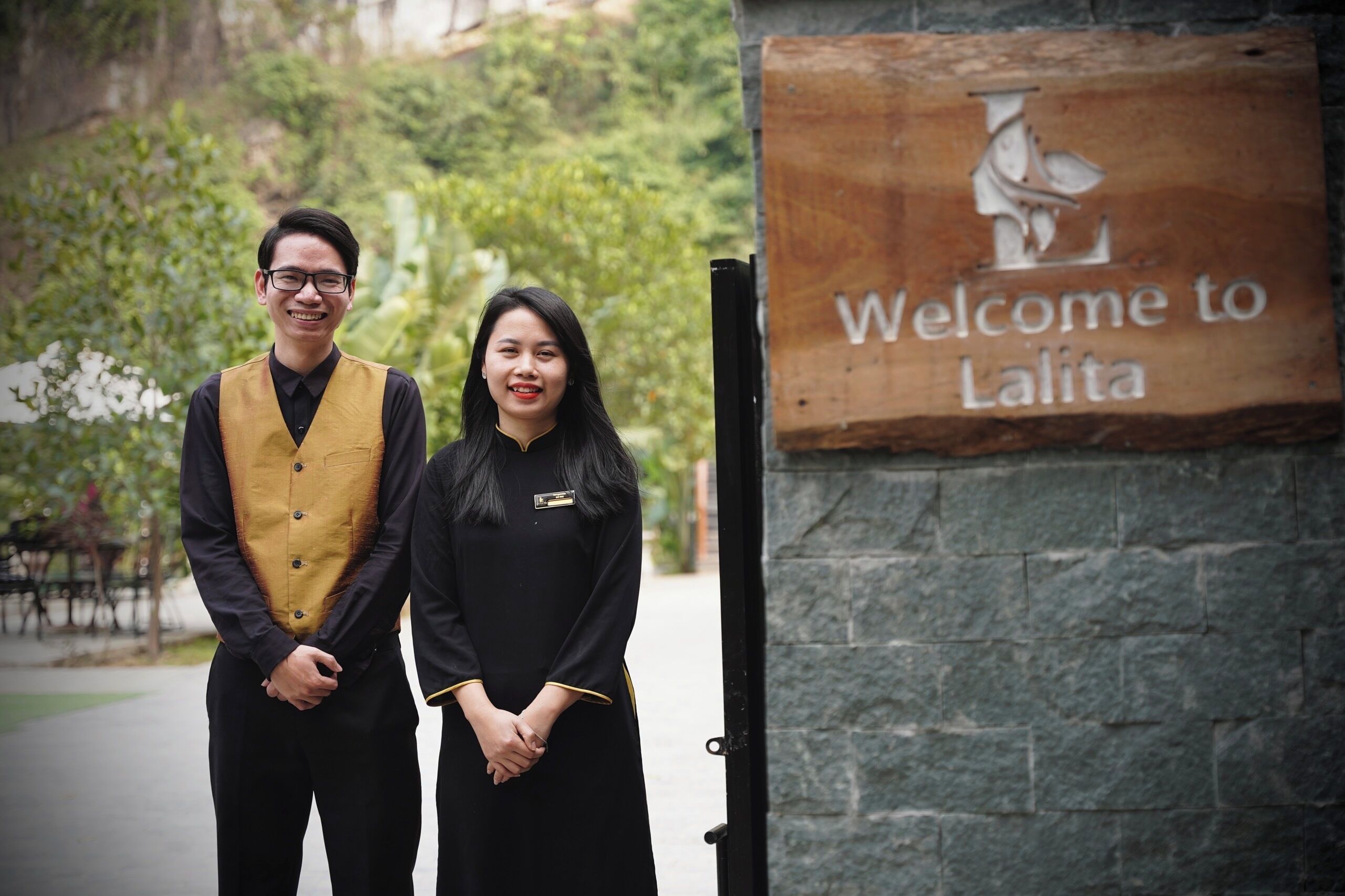 Dos personas de pie frente a un cartel que dice "Welcome to Lalita".