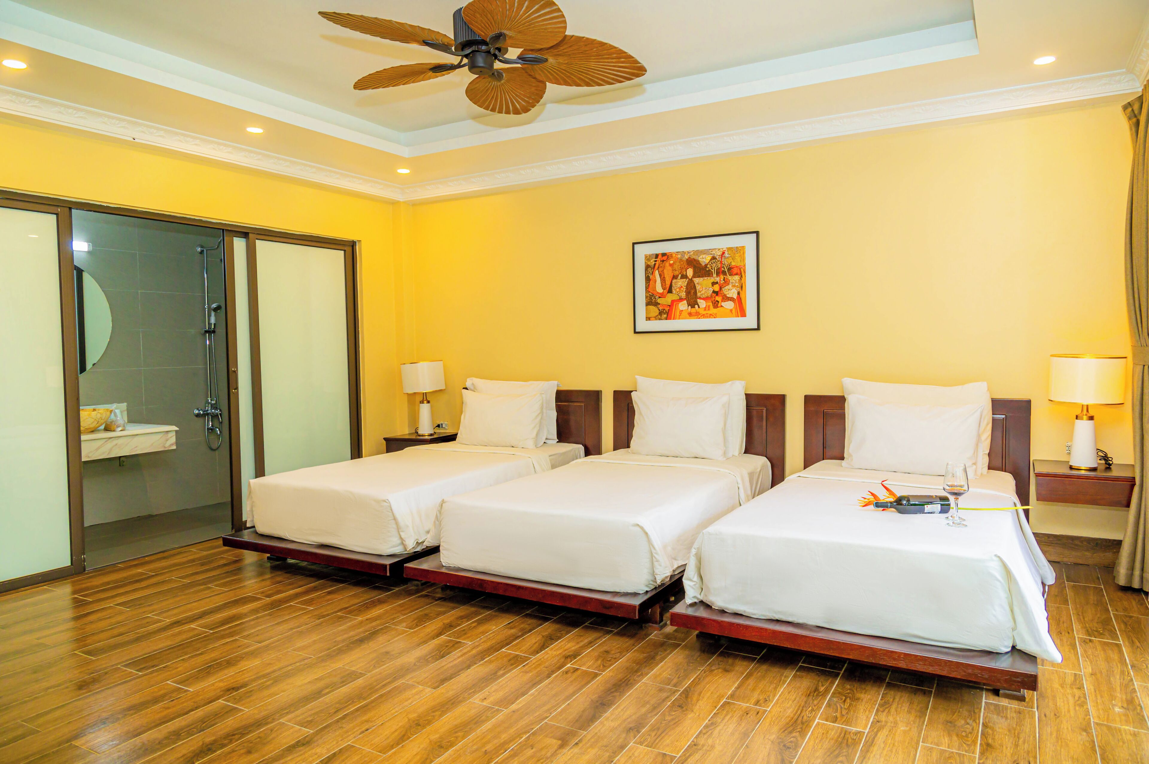 Habitación de hotel con dos camas individuales, ducha, un cuadro en la pared y ventilador de techo.