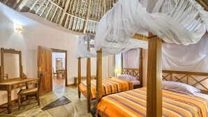 A room with a four-poster bed, a wooden desk, and a stone floor.