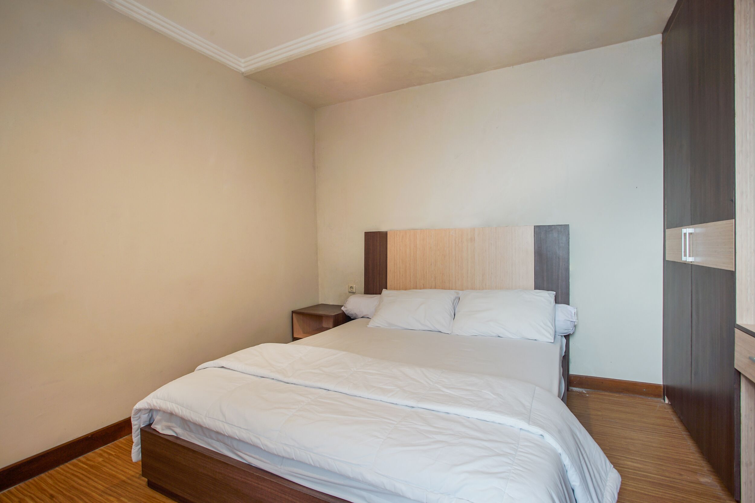 A bedroom with a bed, a nightstand, and a wooden headboard.