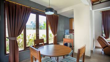 A dining area with a round wooden table, striped cushioned chairs, and brown curtains.