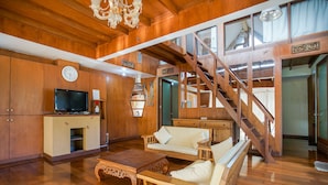 A spacious living room with wooden floors, a staircase, a television, and a sofa. - Bedugul Lake View Villa (Buleleng)