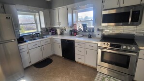 A modern kitchen with stainless steel appliances, white cabinetry, and a window providing natural light. - Quiet Space with Spacious Yard for Parking in Nice Community  (East Millsboro)